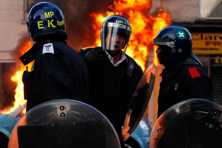 <a><img class="size-full wp-image-1785412" title="Riot police talk in front of a burning car during riots in Clarence Road, Hackney on August 8, 2011 in London, England. (Dan Istitene/Getty Images)" src="https://www.theepochtimes.com/assets/uploads/2015/09/Police120799868.jpg" alt="" width="750" height="500"/></a>