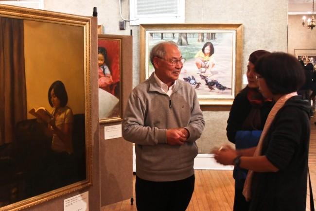 Prof. Zhang Kunlun, former director of the Institute of Shandong Academy of Fine Arts, speaks to guests about one of the paintings in the NTD Television's Oil Painting Competition. Zhang is the Commissioner of Judges for the competition. (BENJAMIN CHASTEEN/THE EPOCH TIMES)