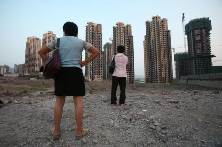 The Chinese real estate market is about to have a new tax added. Pictured, two women in Chongqing are looking at apartment buildings under construction. (AFP/Getty Images)