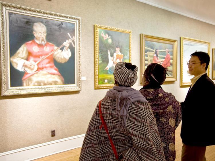 A representative of New Tang Dynasty Television discusses paintings with gallery visitors at the NTD TV Global Chinese Figure Painting Competition exhibition that opened Sunday Nov. 29 at the Salmagundi Club on Fifth Avenue. (Aloysio Santos/The Epoch Times)