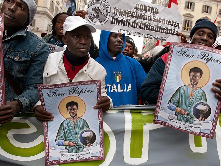 <a><img src="https://www.theepochtimes.com/assets/uploads/2015/09/sanpap95622058.jpg" alt="Protesters march in Rome during a demonstration against all sorts of racism. Placards show 'San Papier, the Patron Saint of the migrants of the earth'. (Vincenzo Pinto/AFP/Getty Images)" title="Protesters march in Rome during a demonstration against all sorts of racism. Placards show 'San Papier, the Patron Saint of the migrants of the earth'. (Vincenzo Pinto/AFP/Getty Images)" width="320" class="size-medium wp-image-1823282"/></a>