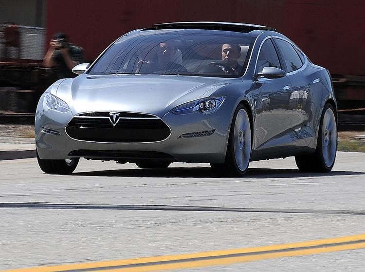 <a><img src="https://www.theepochtimes.com/assets/uploads/2015/09/tesla85622681.jpg" alt="Tesla Motors Chairman and CEO Elon Musk (in driver's seat) and chief designer Franz von Holzhausen (in passenger seat) drive the new Tesla Model S all-electric sedan at the car's unveiling in Hawthorne, California on March 26, 2009. (Robyn Beck/AFP/Getty Images)" title="Tesla Motors Chairman and CEO Elon Musk (in driver's seat) and chief designer Franz von Holzhausen (in passenger seat) drive the new Tesla Model S all-electric sedan at the car's unveiling in Hawthorne, California on March 26, 2009. (Robyn Beck/AFP/Getty Images)" width="320" class="size-medium wp-image-1828223"/></a>