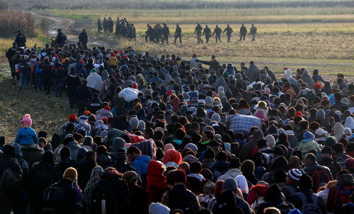 Migrants make their way toward a group of Slovenian soldiers after crossing from Croatia, in Dobova, near a border crossing between Croatia and Slovenia Wednesday, Oct. 21, 2015. A massive influx of migrants has increased tensions in the Balkans, which saw years of war in 1990s. Tense Balkan neighbors have been accusing each other of mishandling the flow of hundreds of thousands of people through the region toward Western Europe. (AP Photo/Darko Bandic)