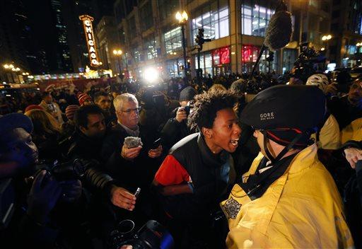 Lamon Reccord, second from right, yells at a Chicago police officer "Shoot me 16 times" as he and others march through Chicago's Loop on Wednesday, Nov. 25, 2015, one day after murder charges were brought against police officer Jason Van Dyke in the killing of 17-year-old Laquan McDonald, in Chicago. (AP Photo/Charles Rex Arbogast)