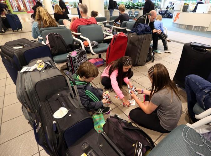 Liam Everett (L), 8, Chloe Betts (C), 10, and Isabella Everett, 10, of North Carolina, play a card game, at Orlando International Airport in Orlanda, Fla., on Jan. 22, 2016. (Red Huber/Orlando Sentinel via AP)