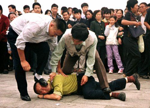 Chinese police violently detain a practitioner of the spiritual discipline Falun Gong on Tiananmen Square in Beijing on Oct. 1, 2000. (AP Photo/Chien-min Chung)