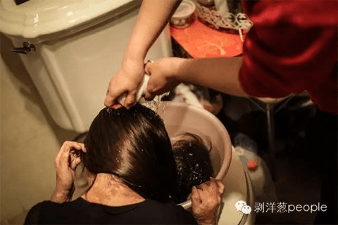 Zhou Yan washing her hair with the help of her mother. (via Beijing News)