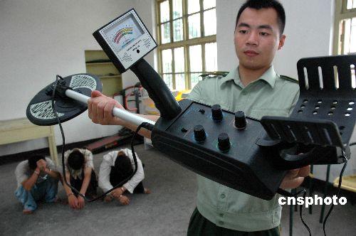 A policeman shows off the metal detector used by three tomb raiders after their arrest in July 2007. (Sohu)