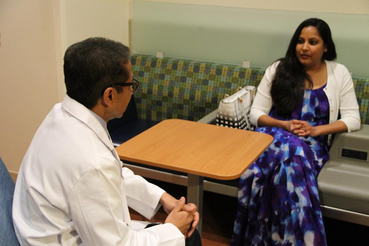 Dr. Naren Ramakrishna (L) speaks with Rhea Birusingh before she undergoes proton therapy to treat a tumor found behind her eye during her pregnancy. Rhea is the first patient to be treated at the new proton therapy center. (UF Health Cancer Center–Orlando Health)