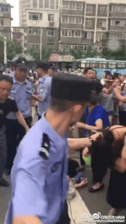 A policeman grabs a woman's hair. (via Sina Weibo)