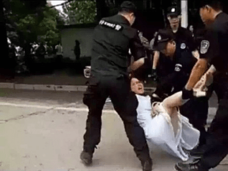 Hubei police drag a woman demonstrator down a street. (Screenshot via Youtube)