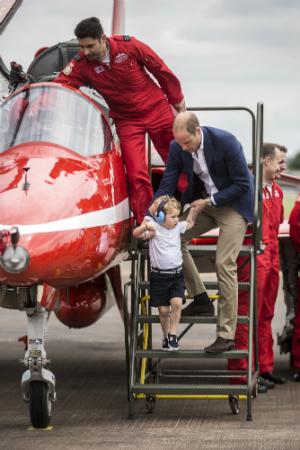 Prince George is lifted down from the cockpit of a red arrows aircraft as his father Prince William, Duke of Cambridge looks on during a visit to the Royal International Air Tattoo at RAF Fairford on July 8, 2016 in Fairford, England. (Richard Pohle - WPA Pool/Getty Images)