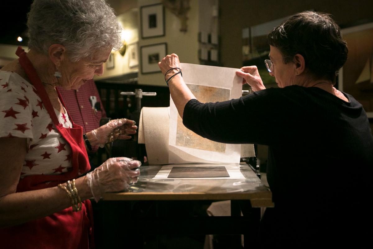 (L-R) Carol Brody and Patricia Wynne use the press during the Salmagundi Club's Monotype Party on July 12, 2016. (Samira Bouaou/Epoch Times)