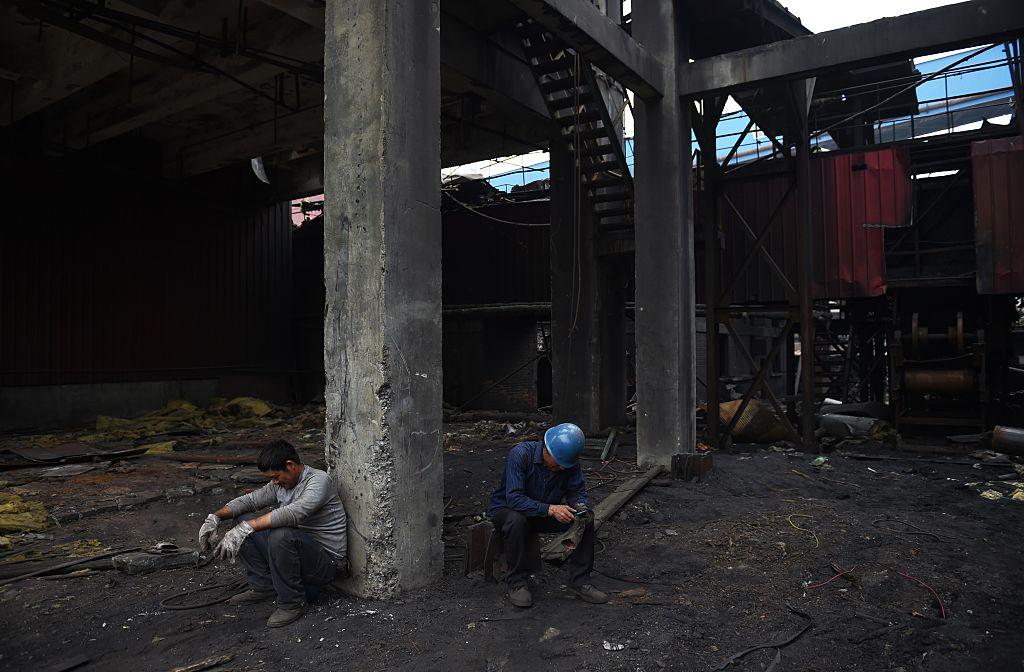 Demolition workers take a rest after cleaning up an abandoned building at the Shougang Capital Iron and Steel Plant in Beijing on May 28, 2015. (Greg Baker/AFP/Getty Images)