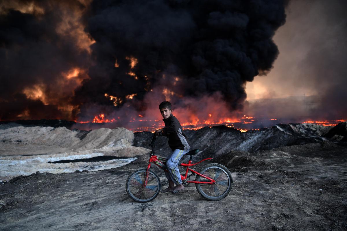 An Iraqi boy passes an oil field that was set on fire by retreating ISIS extremists ahead of the Mosul offensive in Qayyarah, Iraq, on Oct. 21. (Carl Court/Getty Images)