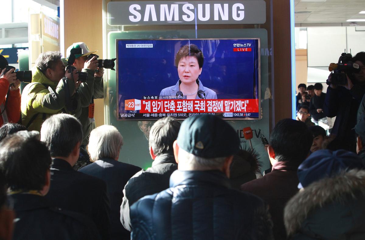 People watch a TV screen showing the live broadcast of South Korean President Park Geun-hye's addressing to the nation, at the Seoul Railway Station in Seoul, South Korea on Nov. 29, 2016. (AP Photo/Ahn Young-joon)