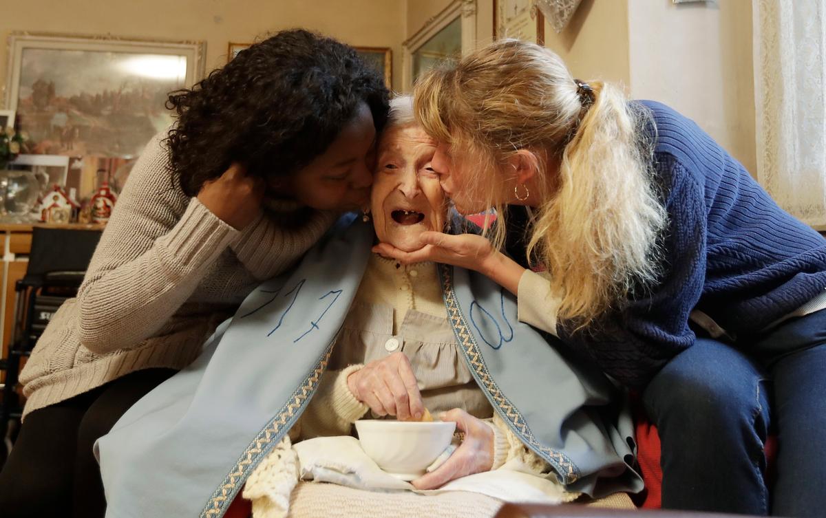 Emma Morano, 117 years hold, is kissed by her caretakers Malgorzat Ceglinska (R) and Yamilec Vergara, on the day of her birthday in Verbania, Italy, on Nov. 29, 2016. (AP Photo/Antonio Calanni)
