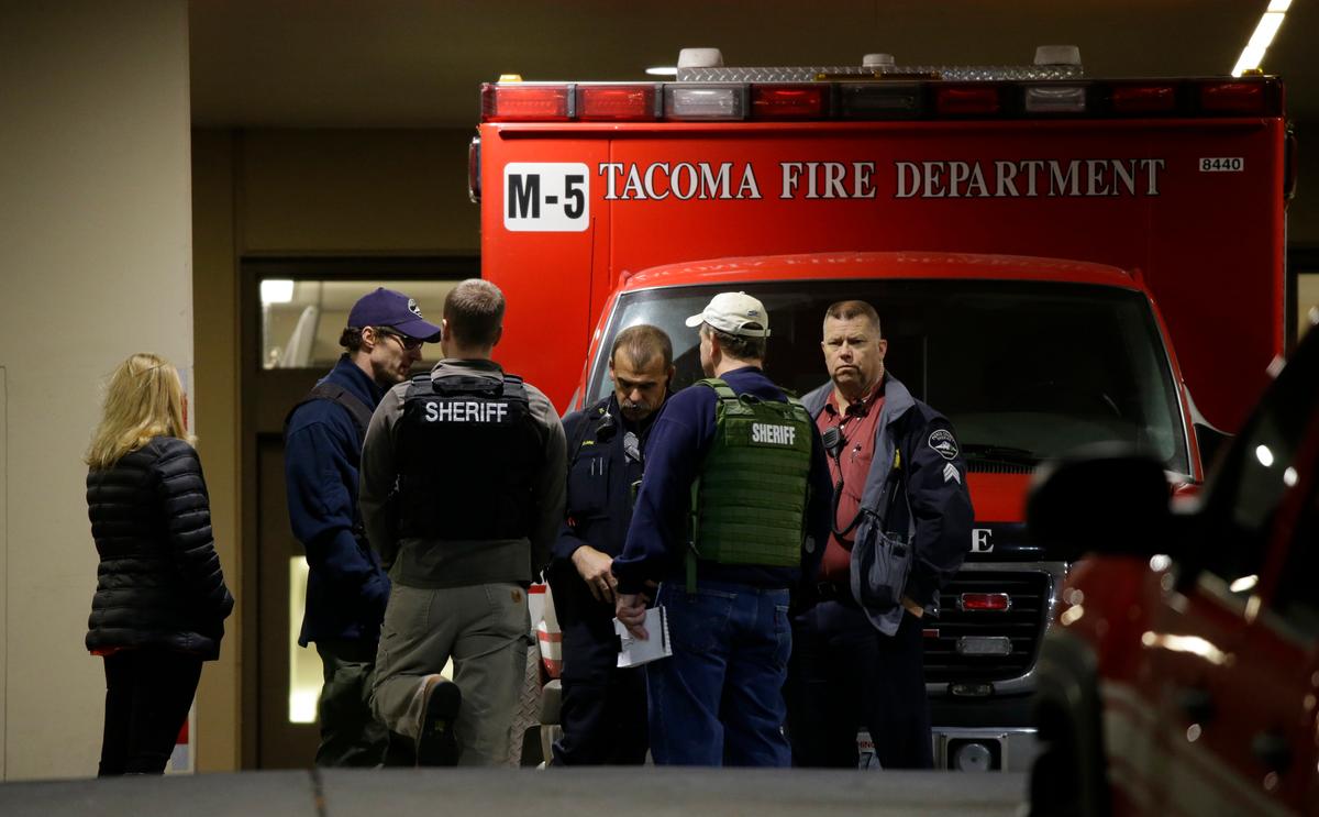 Law enforcement officers gather in front of an ambulance at Tacoma General Hospital, where a Tacoma Police officer was taken after being shot while responding to a call in Tacoma, Wash. on Nov. 30, 2016. (AP Photo/Ted S. Warren)
