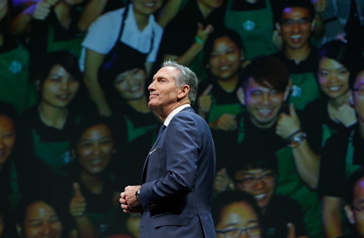 Starbucks CEO Howard Schultz walks in front of a photo of Starbucks baristas, at the coffee company's annual shareholders meeting in Seattle, in this file photo.<br/>(AP Photo/Ted S. Warren)