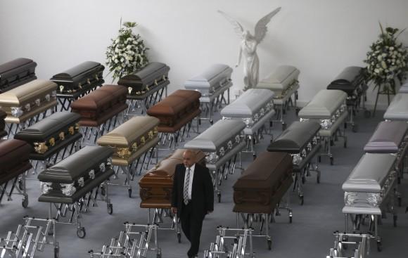 A funeral employee walks past coffins containing the remains of the victims of the Colombian air tragedy are lined up in the parking garage of the San Vicente funeral home in Medellin, Colombia, on Dec. 1, 2016. (AP Photo/Fernando Vergara)