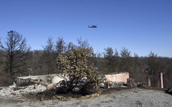 An Air National Guard helicopter flies over Gatlinburg, Tenn., on Dec. 1, 2016 searching for problems following Monday's devastating wildfire. (Michael Patrick/Knoxville News Sentinel via AP)