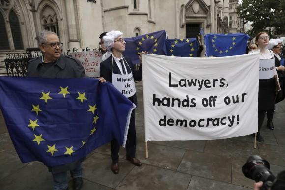Supporters of the pro-democracy group "Invoke Article 50 Now!" hold a banner as pro-EU membership supporters hold EU flags on the first day of Gina Miller's, a founder of investment management group SCM Private, lawsuit at the High Court, in London, in this file photo. (AP Photo/Matt Dunham, File)