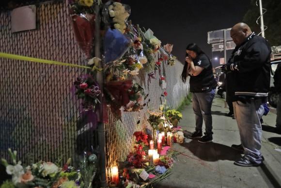 Sol Rodriguez, center, and Aaron Torres visit a shrine for the victims of a warehouse fire near the site in Oakland, Calif., on Dec. 4, 2016. (AP Photo/Marcio Jose Sanchez)