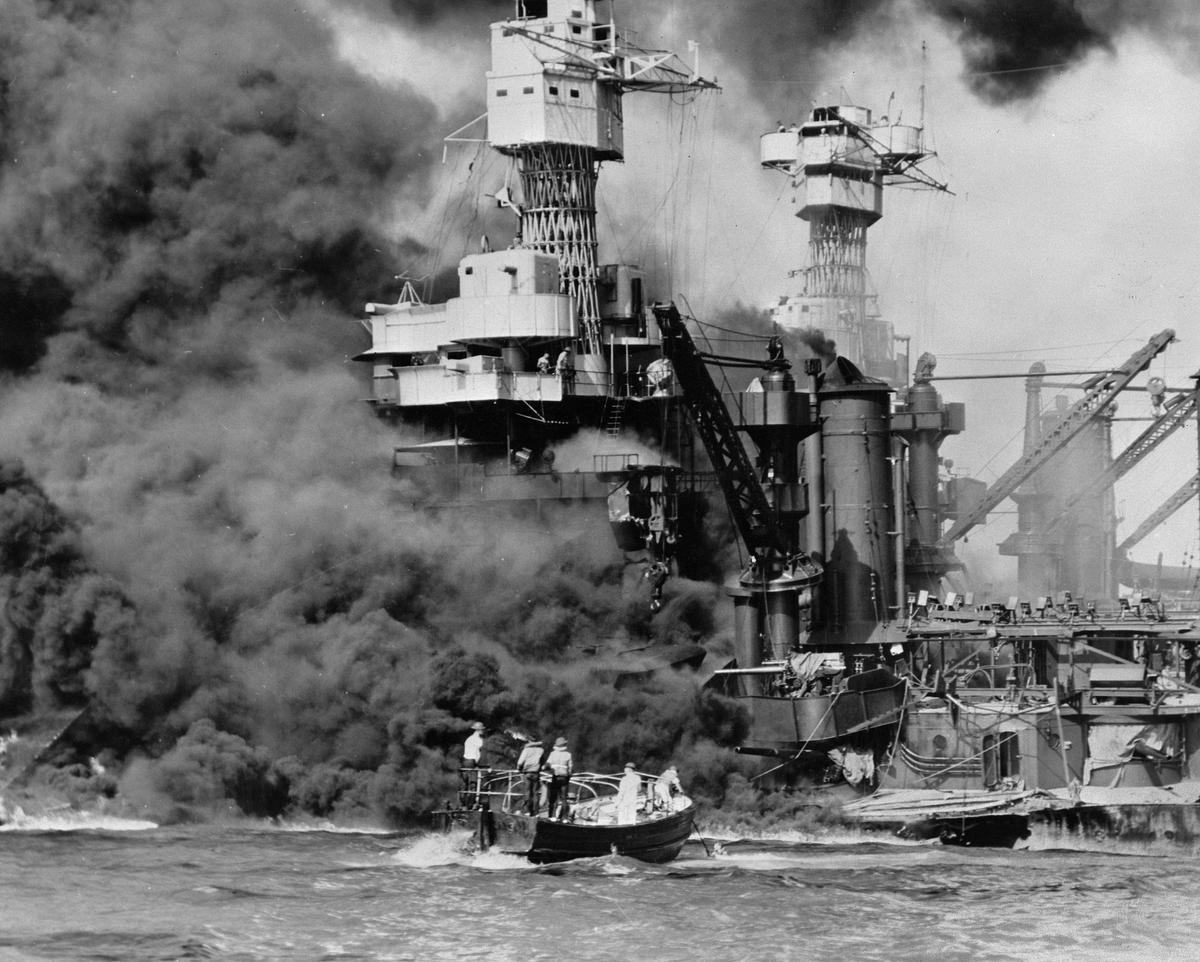 A small boat rescues a seaman from the USS West Virginia burning in the foreground in Pearl Harbor, Hawaii on Dec. 7. (U.S. Navy via AP)