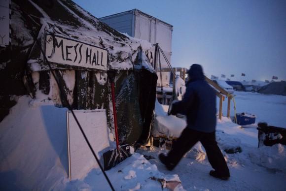 Ray Franks, of New York, carries a case of water into a mess hall at the Oceti Sakowin camp where people have gathered to protest the Dakota Access oil pipeline in Cannon Ball, N.D. on Dec. 6, 2016. An overnight storm brought several inches of snow, winds gusting to 50 mph and temperatures that felt as cold as 10 degrees below zero. (AP Photo/David Goldman)