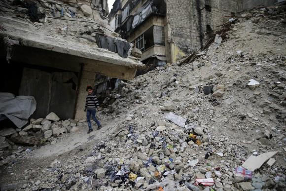 A Syrian girl walks amid the wreckage of damaged buildings and shops in the western city of Aleppo, Syria, on Dec 5, 2016. (AP Photo/Hassan Ammar)