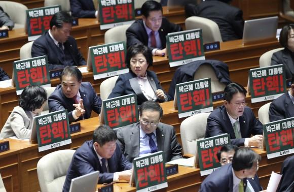 Lawmakers of opposition parties wait for the plenary session as they put placards reading "President Park Geun-hye, Impeachment" at the National Assembly in Seoul, South Korea, on Dec. 8, 2016. (AP Photo/Lee Jin-man)