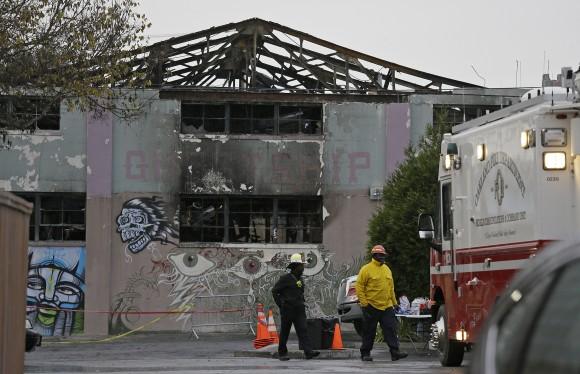 A pair of Oakland fire officials walk past the remains of the Ghost Ship warehouse fire in Oakland, Calif., on Dec. 7, 2016. (AP Photo/Eric Risberg)