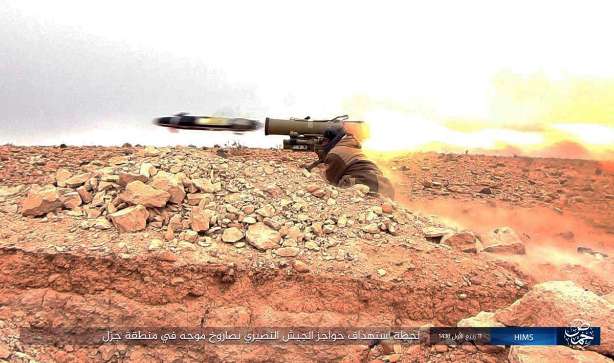 This image posted online on Dec. 10, 2016, by supporters of the Islamic State militant group on an anonymous photo sharing website, purports to show a gunman firing an anti-tank missile at Syrian troops north of Palmyra city, in Homs Provence, Syria. (Militant Photo via AP)