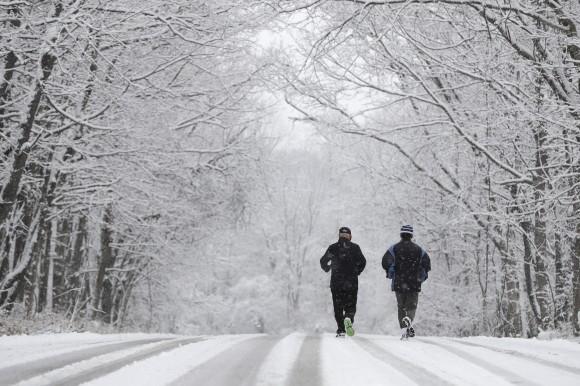 Ken Perry and Stan Ly go for a run in Eagle Creek Park, in Indianapolis as snow falls on Dec. 13, 2016. (AP Photo/Darron Cummings)