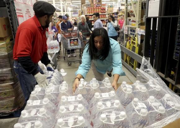 H-E-B employees remove bottles of water from a crate to hand out to customers in Corpus Christi, Texas, on Dec. 15, 2016. (Gabe Hernandez/Corpus Christi Caller-Times via AP)