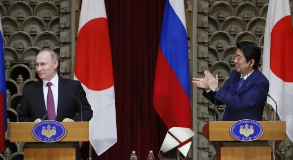 Japanese Prime Minister Shinzo Abe, right, applauds as Russian President Vladimir Putin reacts during their joint press conference in Tokyo, Japan, on Dec. 16, 2016. (AP Photo/Alexander Zemlianichenko, Pool)