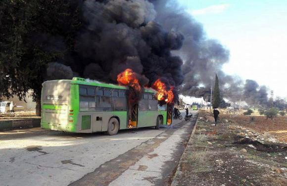 In this photo released by the Syrian official news agency SANA, smoke rises in green government buses, in Idlib province, Syria on Dec. 18, 2016. (SANA via AP)