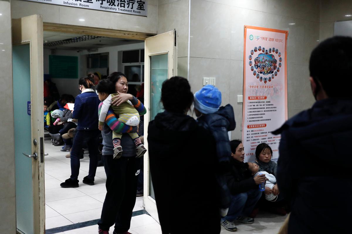 Parents carrying their children wait to see doctors at a children's hospital in Beijing on Dec. 18, 2016. (AP Photo/Andy Wong)