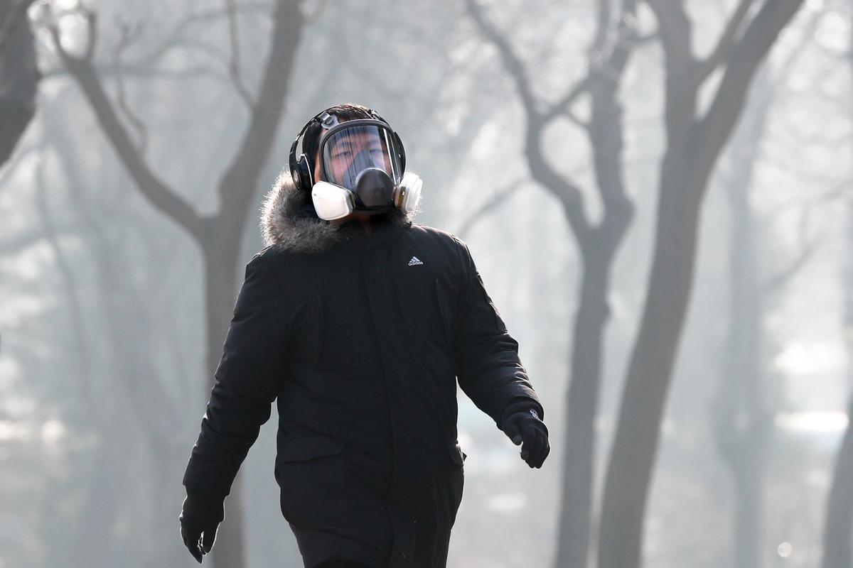 A man wearing a mask for protection against pollution exercise at Ritan Park during a heavily polluted day in Beijing, on Dec. 19, 2016. (AP Photo/Andy Wong)