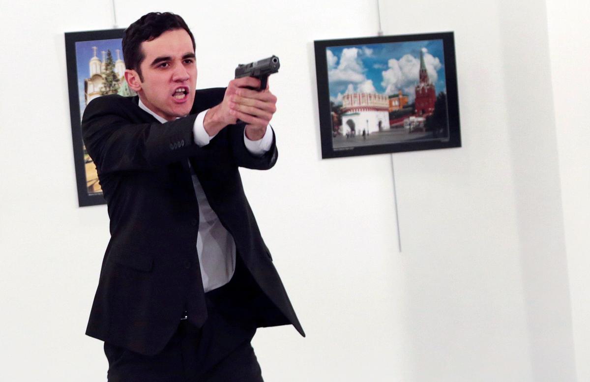 A man identified as Mevlut Mert Altintas holds up a gun after shooting Andrei Karlov, the Russian Ambassador to Turkey, at a photo gallery in Ankara, on Dec. 19, 2016. (AP Photo/Burhan Ozbilici)