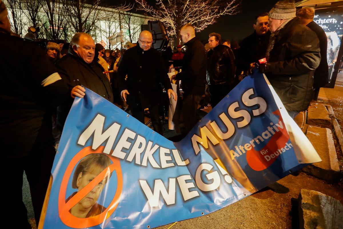 People hold a poster reading: 'Merkel must go' as they attend a demonstration of the Alternative for Germany, AfD, in front of the Chancellery in Berlin on Dec. 21, 2016. (AP Photo/Markus Schreiber)