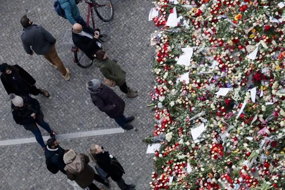 People stand near candles at the Christmas market, three days after a truck ran into the crowd and killed several people, near the Kaiser Wilhelm Memorial Church in Berlin, on Dec. 22, 2016. (AP Photo/Markus Schreiber)
