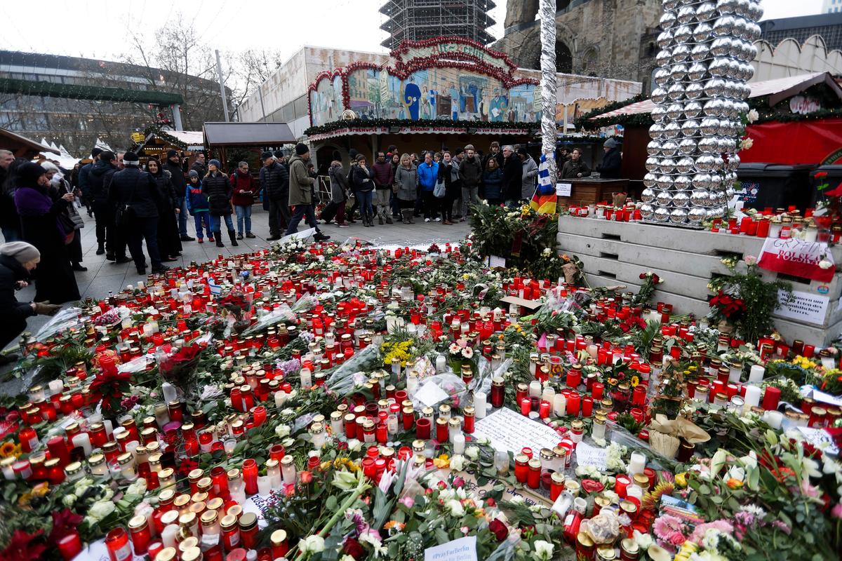 People stand around candles at the reopened Christmas market, three days after a truck ran into the crowd and killed several people, at the Kaiser Wilhelm Memorial Church in Berlin, on Dec. 22, 2016. (AP Photo/Markus Schreiber)