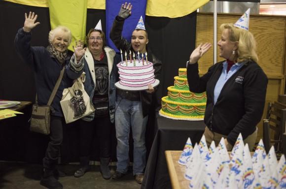 Michele Frymen, from left, Christy Anderson and Jacob Anderson, all from Columbus, hold up a birthday cake and wave as they get their picture taken during some festivities in the food court as part of the 60th birthday celebration for Colo, the nation's oldest living gorilla, at the Columbus Zoo and Aquarium, on Dec. 22, 2016. (AP Photo/Ty Wright)