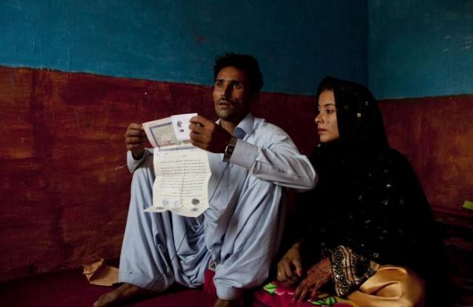 In this photo taken on Thursday, Dec. 1, 2016, Hamid Brohi shows a court document as he sits with his wife Jeevti in Pyaro Lundh, Pakistan. The night Jeevti disappeared, her family slept outside to escape Pakistan's brutal summer heat; in the morning she was gone, snatched by a wealthy landlord to whom her parents owed $1,000 dollars. She is one of the estimated 1,000 Christian and Hindu girls taken from their homes every year in Pakistan for supposed repayments of debt, most of them ending up married off to older men and forcibly converted to Islam. (AP Photo/B.K. Bangash)