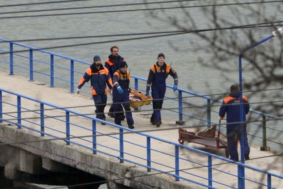 Russian rescue workers carry a body from the wreckage of the crashed plane, at a pier just outside Sochi, Russia on Dec. 25, 2016. Russian ships, helicopters and drones are searching for bodies after a plane carrying 93 people crashed into the Black Sea. (AP Photo/Viktor Klyushin)