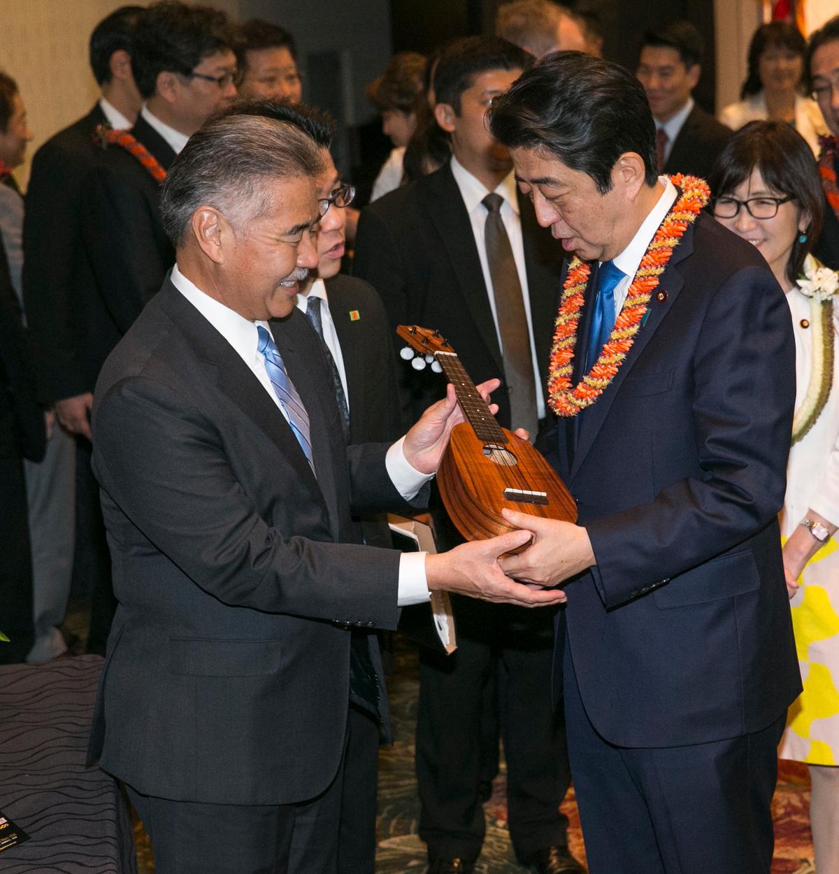 Hawaii Gov. David Ige (L) presents Japanese Prime Minister Shinzo Abe a pineapple-shaped ukulele at a dinner held in Abe's honor, in Honolulu on Dec. 26, 2016. (AP Photo/Marco Garcia)