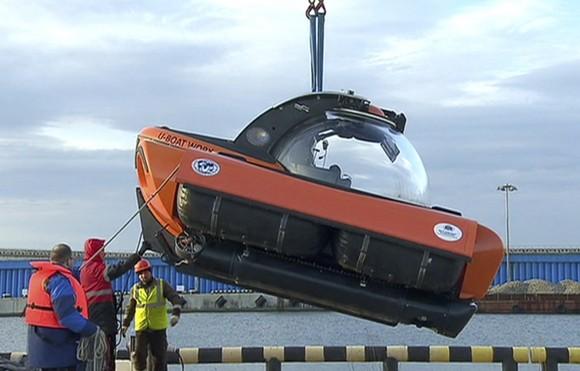 In this Dec. 27, 2016 frame grab made available by Russian Rossiya One TV Channel Emergency Ministry employees unload a submersible to make it ready to join the search for bodies and fragments of the crashed plane, on a pier just outside Sochi, Russia. (Rossiya One TV Channel photo via AP)