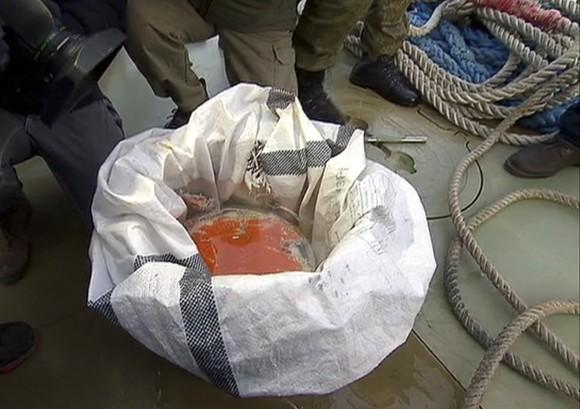 In this Dec. 27, 2016 frame grab made available by Russian Rossiya One TV Channel Emergency Ministry soldiers show a flight recorder of the crashed plane, on a pier just outside Sochi, Russia. (Rossiya One TV Channel photo via AP)