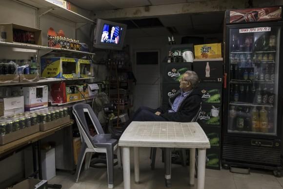 An Israeli grocery store owner watches the US Secretary of State John Kerry speech at the State Department at Washington, in Sderot near the Israel and Gaza border, Wednesday, Dec. 28, 2016. Israeli Prime Minister Benjamin Netanyahu's office is denouncing Secretary of State John Kerry's Mideast policy speech, saying it was "skewed against Israel" and "obsessively" focuses on Israeli settlements. In a statement, Netanyahu's office says the speech "barely touched upon the root of the conflict, Palestinian opposition to a Jewish state in any boundaries." (AP Photo/Tsafrir Abayov)